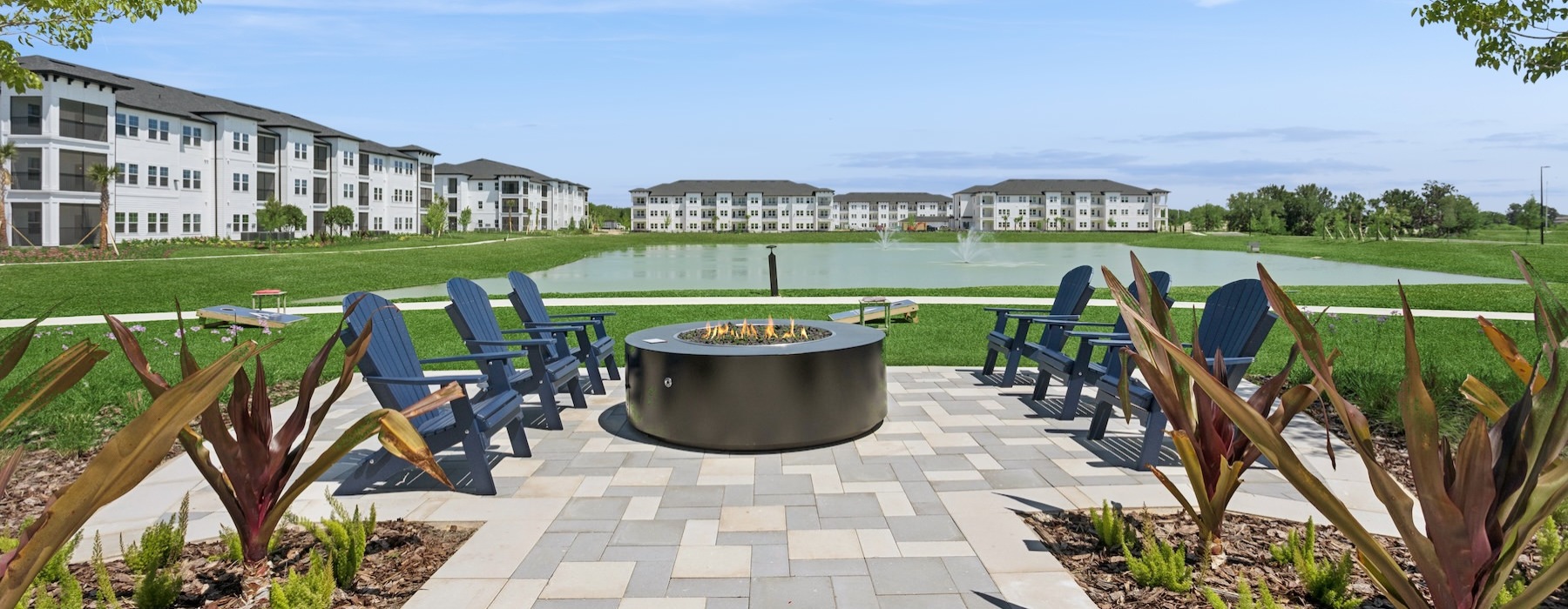 a patio with chairs and a fireplace by a body of water