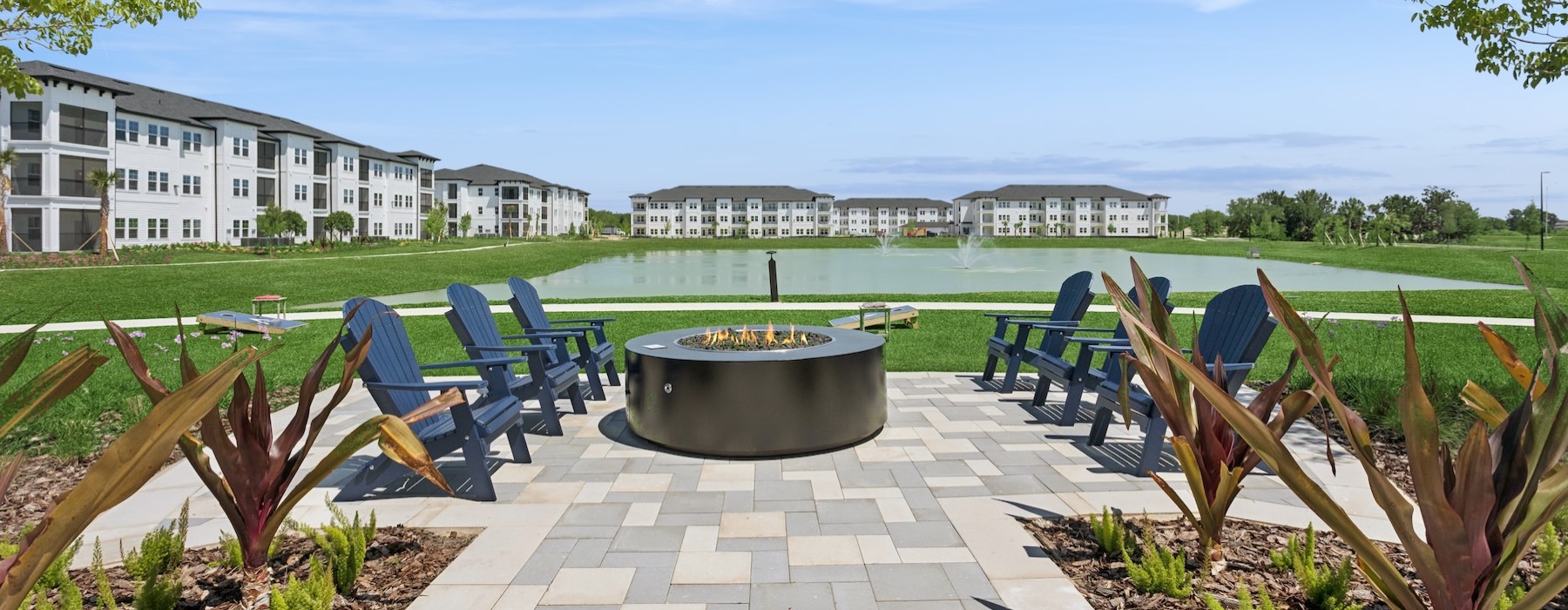 a patio with chairs and a fireplace by a body of water